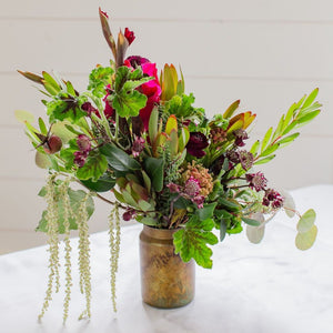 burgundy notes with seasonal greenery in glass vase